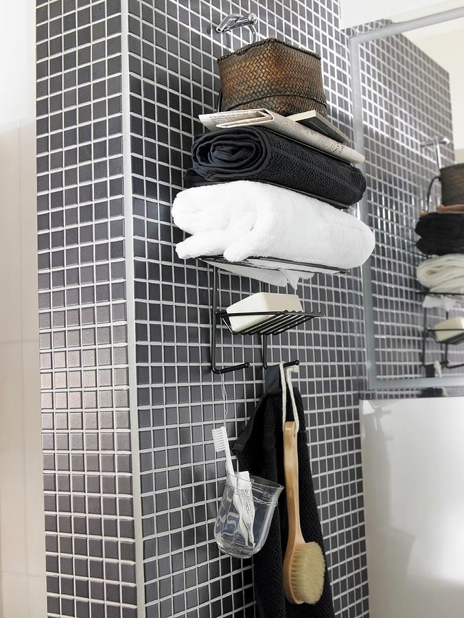 Stacked Towels On Top Of Wall-mounted Shelves With Hooks Below On Grey Mosaic-tiled Wall Photograph by Greenhaus Press