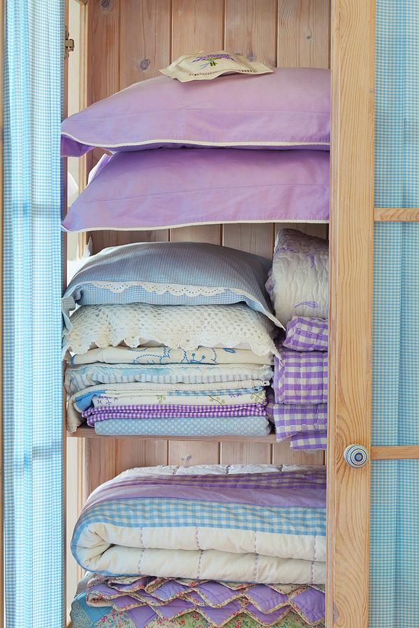 Stacks Of Pastel-blue Bedclothes And Pillows In A Light Wooden Cupboard Photograph by Studio Lipov