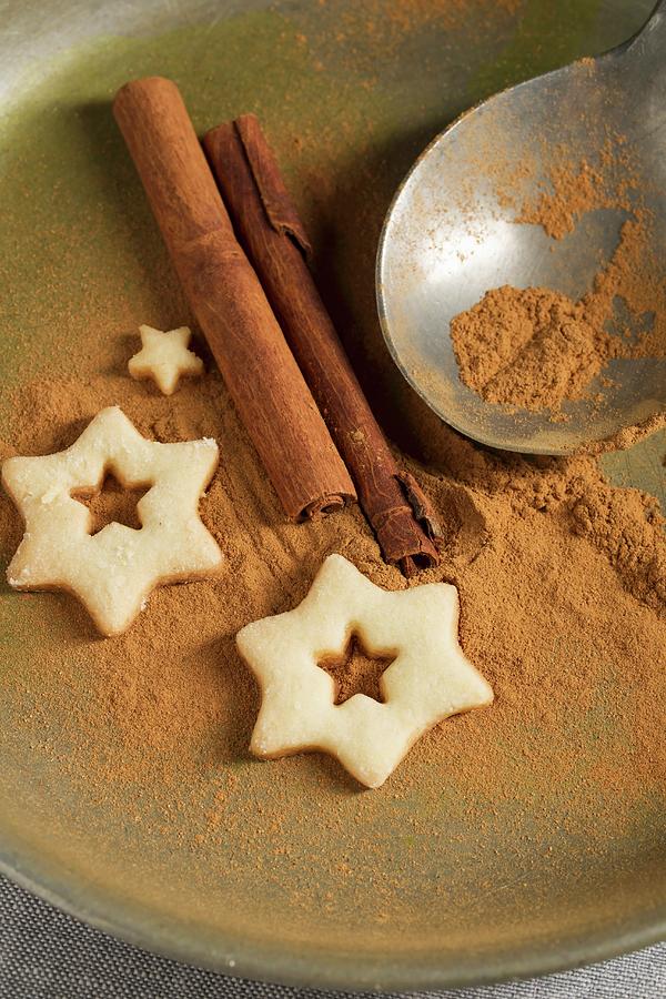 Christmas Photograph - Star-shaped Biscuits, Ground Cinnamon, Cinnamon Sticks And A Spoon by Mandy Reschke