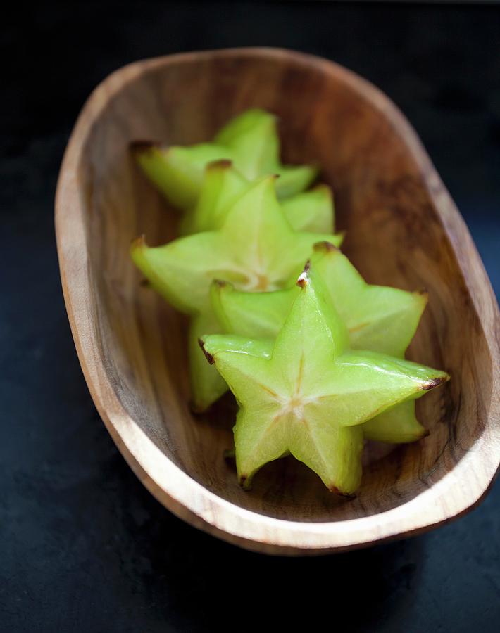 Starfruit In A Small Wooden Bowl On A Black Countertop Photograph by Ryla Campbell