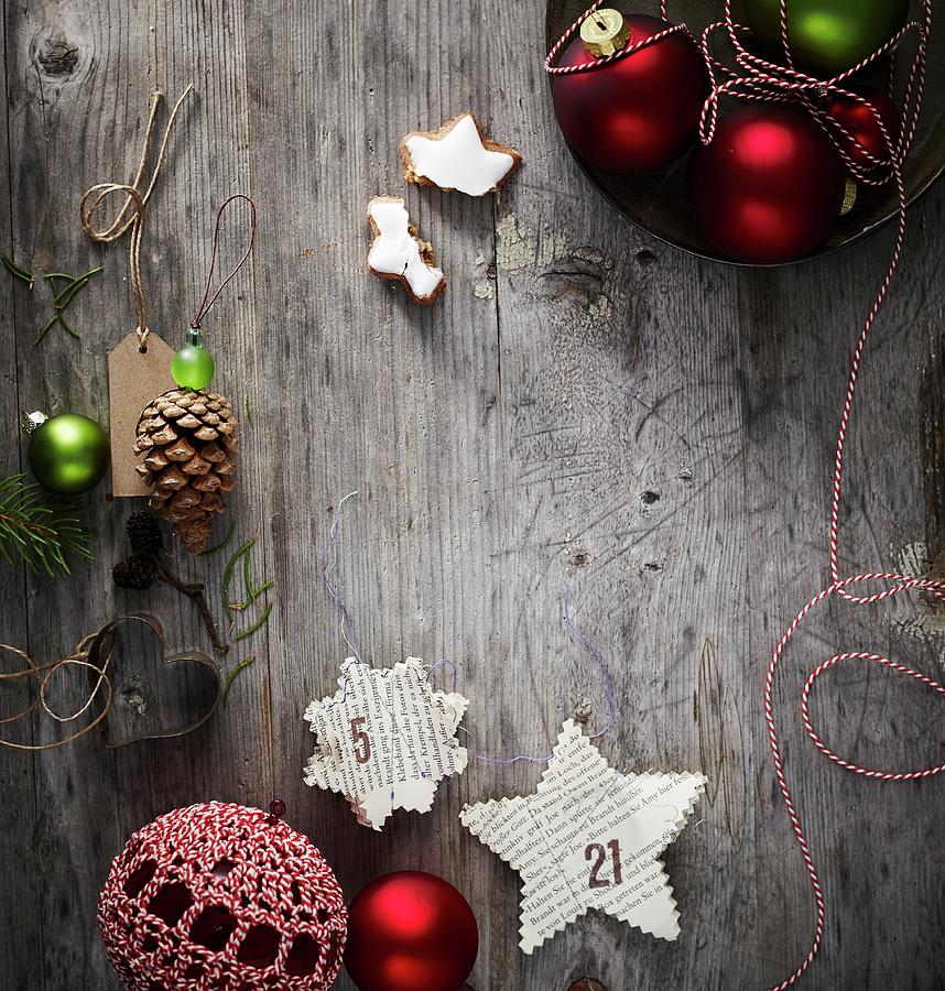 Stars Cut Out Of Book Pages And Other Christmas Decorations On Weathered Wooden Surface Photograph by Andreas Hoernisch