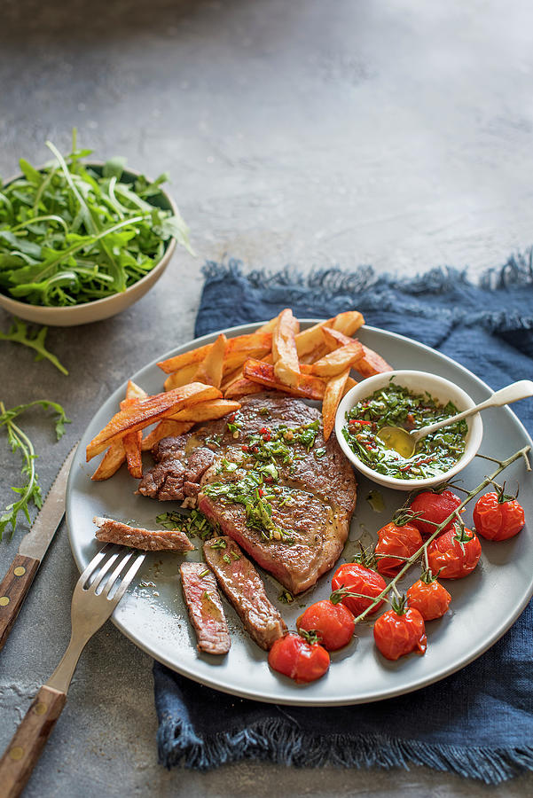 Steak With Chimichurri Sauce, Chips, Rocket And Grilled Tomatoes Photograph by Magdalena Hendey