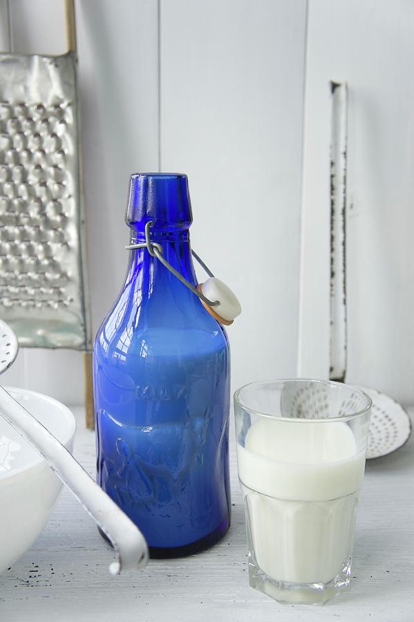 Still-life Arrangement Of Blue Milk Bottle And Full Glass Of Milk Photograph by Martina Schindler
