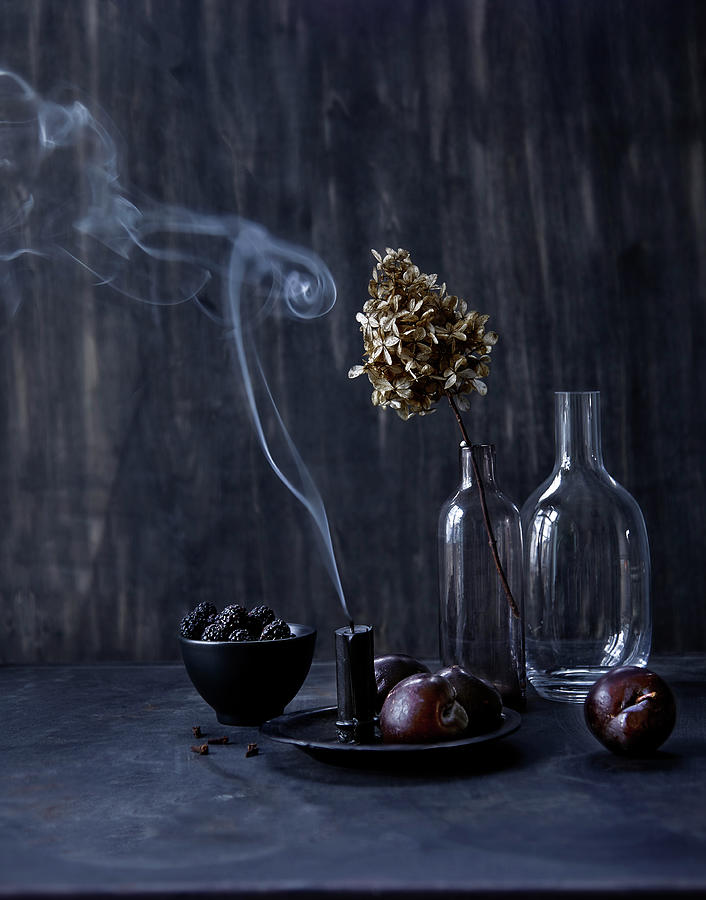 Still-life Arrangement Of Dark Fruit, Glass Bottles And Candle Smoke Photograph by Klaudia Iga Studio