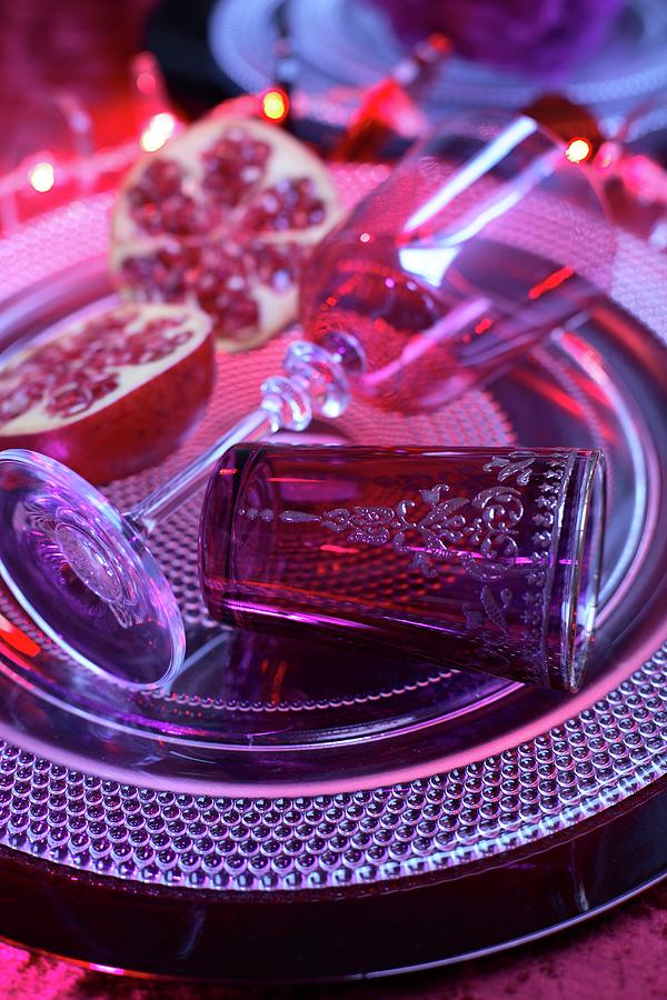 Still-life Arrangement Of Stemmed Glass And Oriental Tea Glass Next To Cut Pomegranate On Platter Photograph by Michal Mrowiec