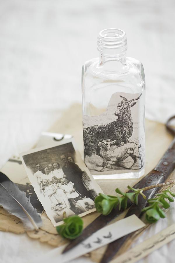 Still-life Arrangement Of Vintage Family Photo And Bottle Decorated With Vintage Picture Of Goats Photograph by Alicja Koll