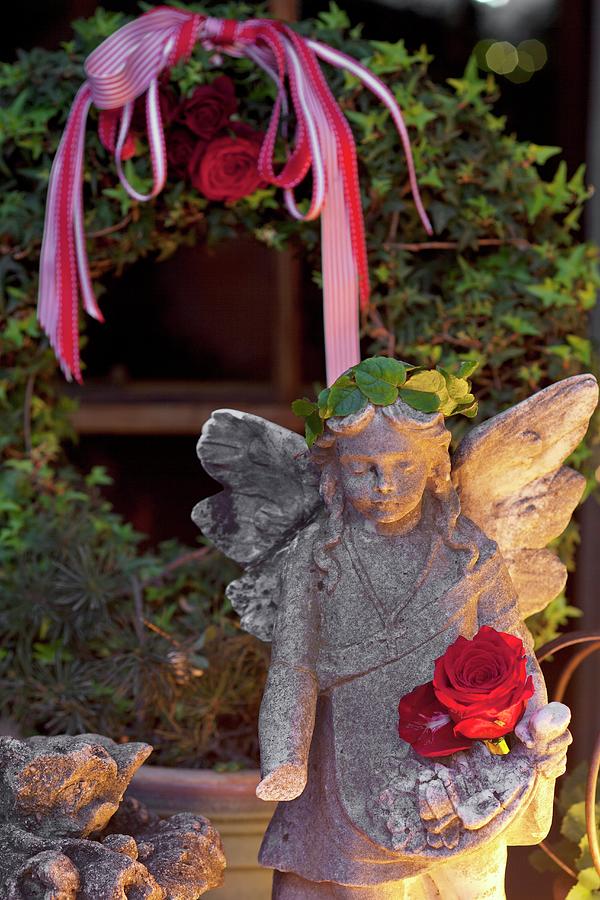 Stone Angel Lit From One Side In Front Of Ivy Wreath In Garden Photograph by Great Stock!