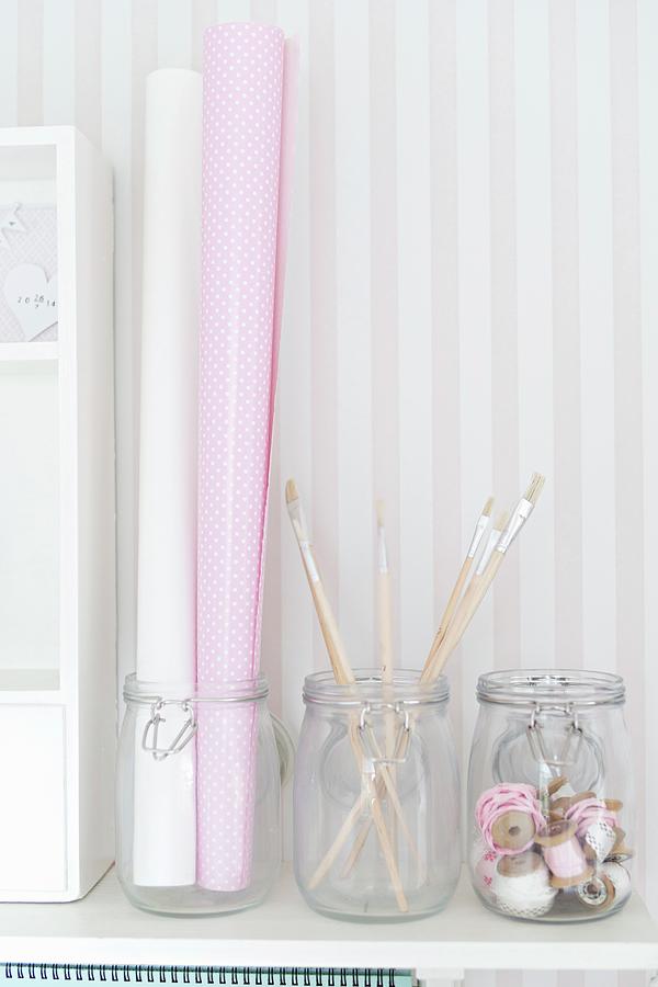 Storage Jars Holding Pretty Paper, Paintbrushes And Ribbons Against Pale, Striped Wallpaper Photograph by Cecilia Mller