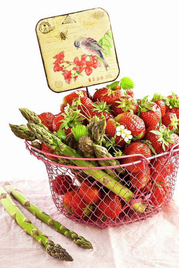 Strawberries And Green Asparagus In A Wire Basket With An Old-fashioned Sign Photograph by Atelier Hmmerle