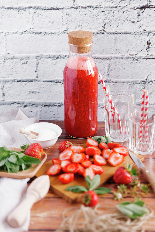 Strawberry Smoothie In A Bottle And Sliced Strawberries On A Wooden Board Photograph by Kuzmin5d