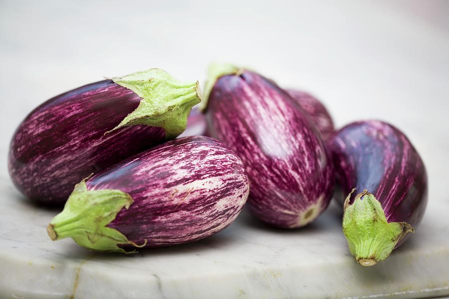Striped Aubergines On A Marble Surface Photograph by John Gagne