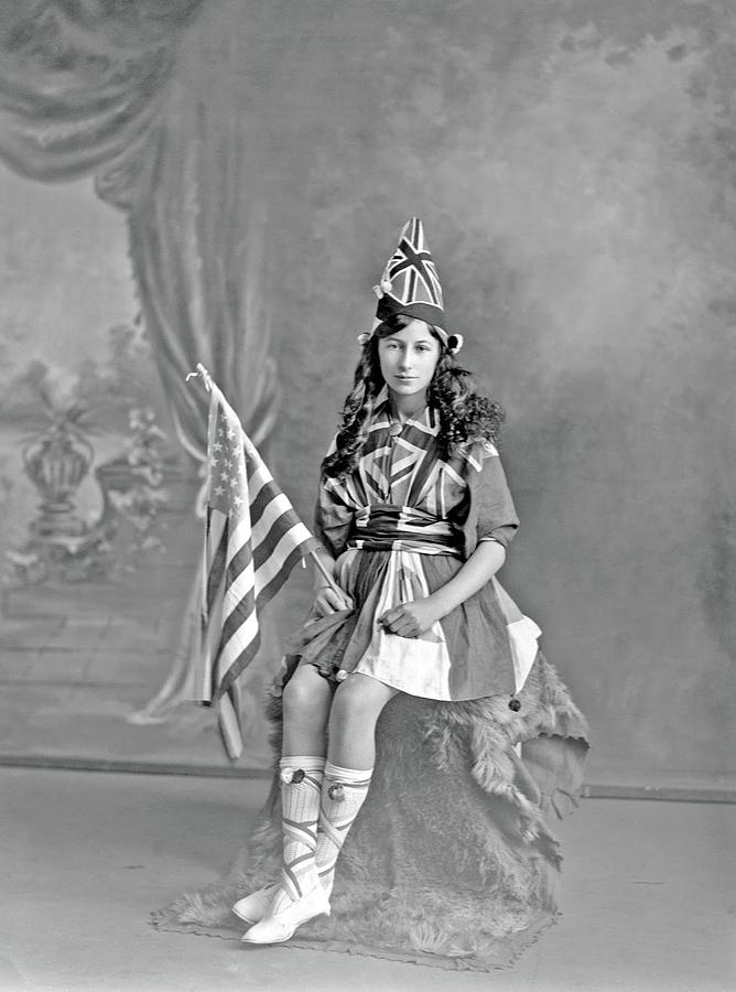 Studio portrait of unidentified girl, dressed in Union Jack flags and holding an American flag, prob Painting by Celestial Images