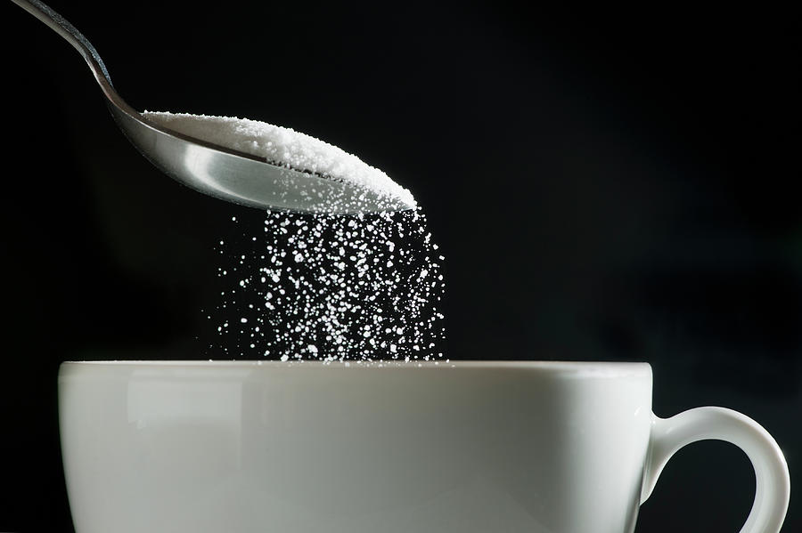 Studio Shot Of Sugar Poured Into Coffee by Tetra Images