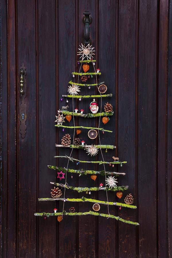 Stylised Christmas Tree Made From Mossy Branches With Natural Decorations And Straw Stars Hanging On Front Door Photograph by Sabine Lscher
