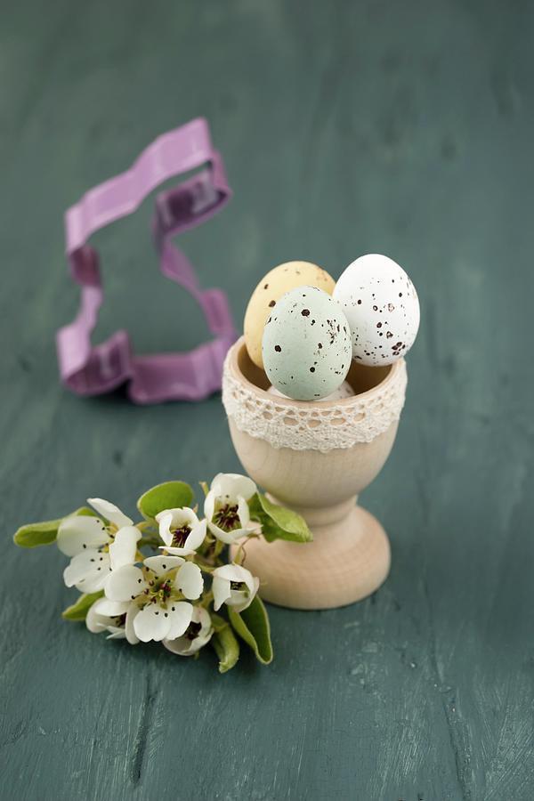 Sugar-coated Chocolate Eggs In Wooden Egg Cup And Pear Blossom Photograph by Mandy Reschke
