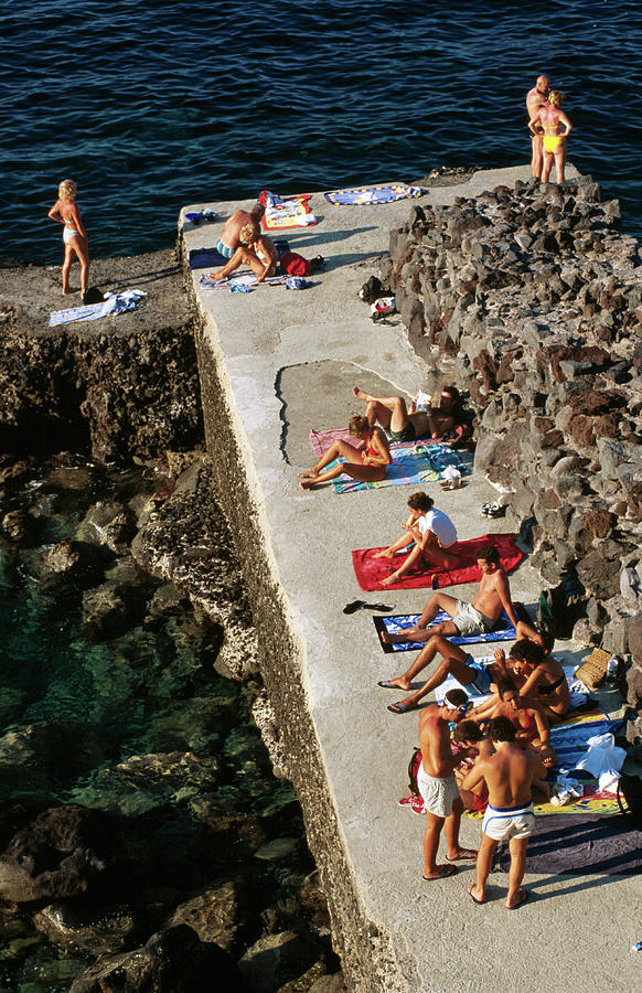 Sunbathers At Sea Wall Of Malfa Marina Photograph by Dallas Stribley
