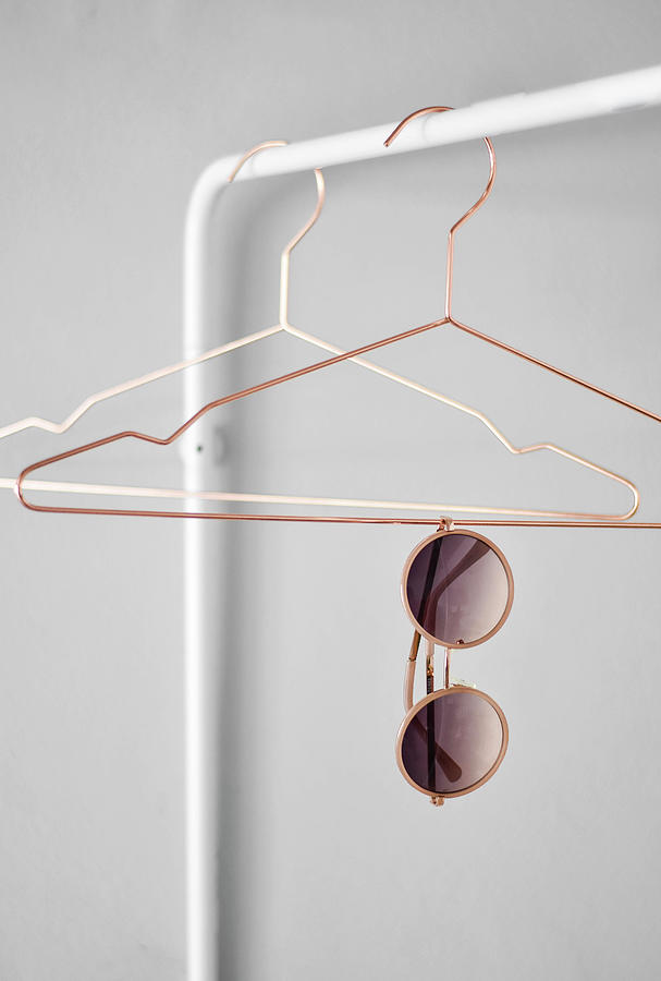 Sunglasses Hanging From Coat Hanger On Clothes Rail Photograph by Agata Dimmich