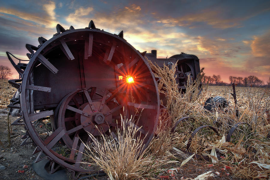 Sunrise through Abandoned Vintage Tractor Wheel Photograph by Peter Herman