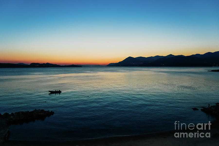 Sunset in a bay with mountains in the background and a small boa Photograph by Joaquin Corbalan