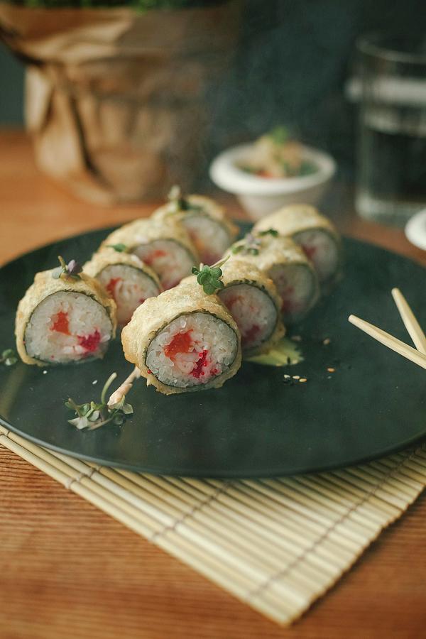 Sushi Rolls With Salmon, Deep Fried In Tempura Batter, On A Black Plate Photograph by Kuzmin5d