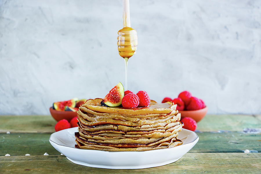 Sweet Breakfast Of Homemade Pancake Tower With Fresh Figs And Raspberries On White Plate, And Flowing Honey From Wooden Honey Dipper Photograph by Yuliya Gontar