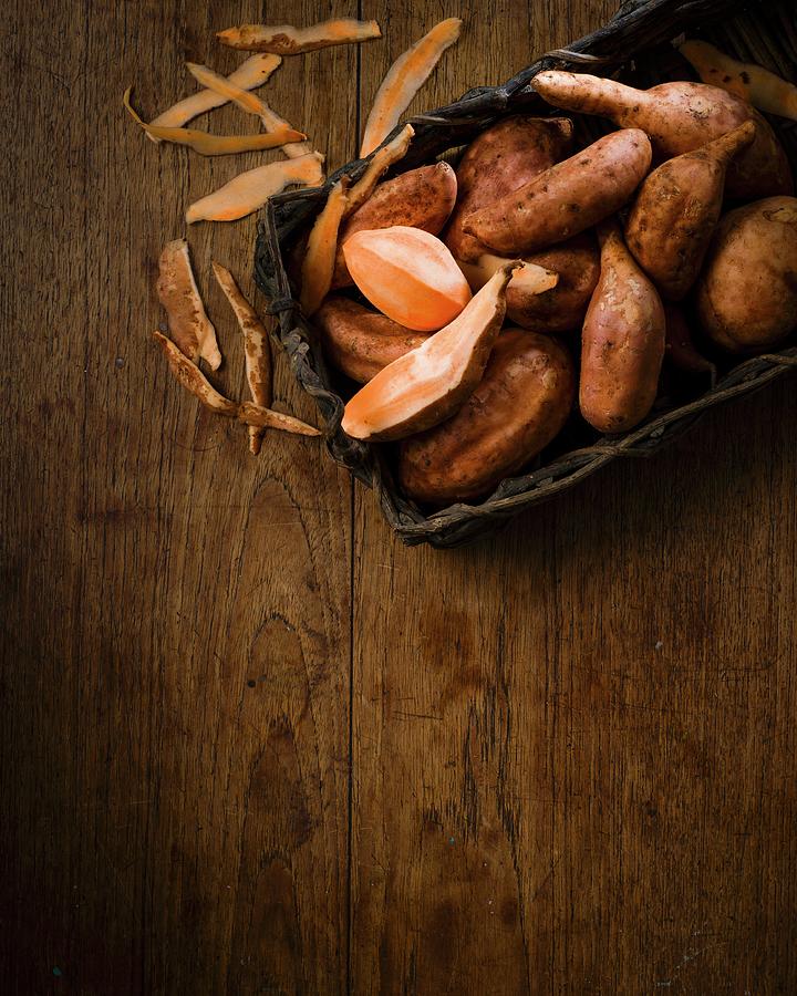 Sweet Potatoes In A Rustic Wooden Basket And Peelings On A Wooden Table Photograph by Great Stock!