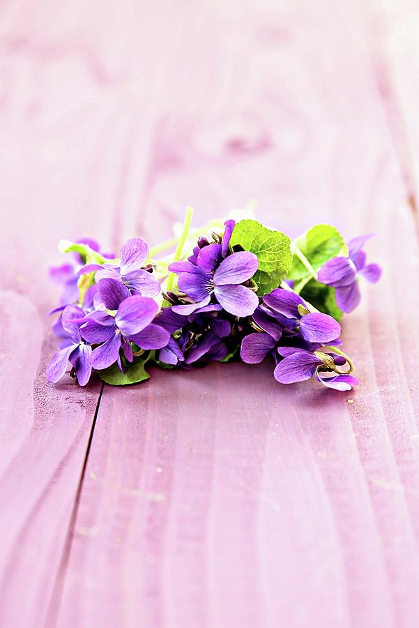 Sweet Violets On Pink Wooden Surface Photograph by Alexandra Panella