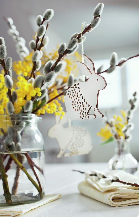 Table Centrepiece Of Willow Catkins, Mimosa Flowers And Easter Bunny Pendants Photograph by Pia Simon