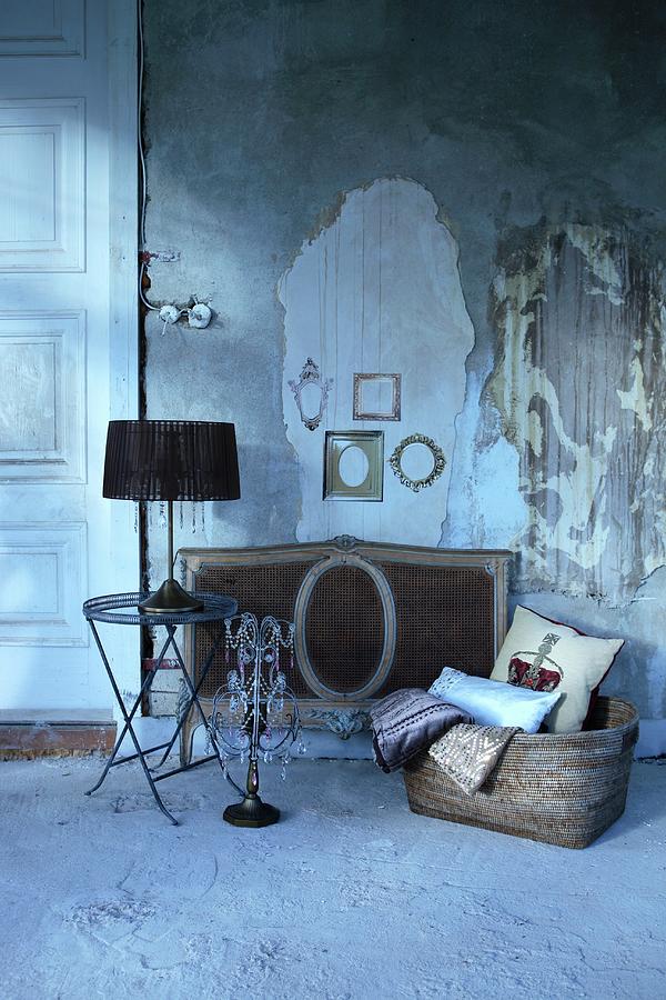 Table Lamp With Black Lampshade On Side Table Next To Candelabra And Basket On Floor In Front Of Wall With Crumbling Plaster Photograph by Michal Mrowiec