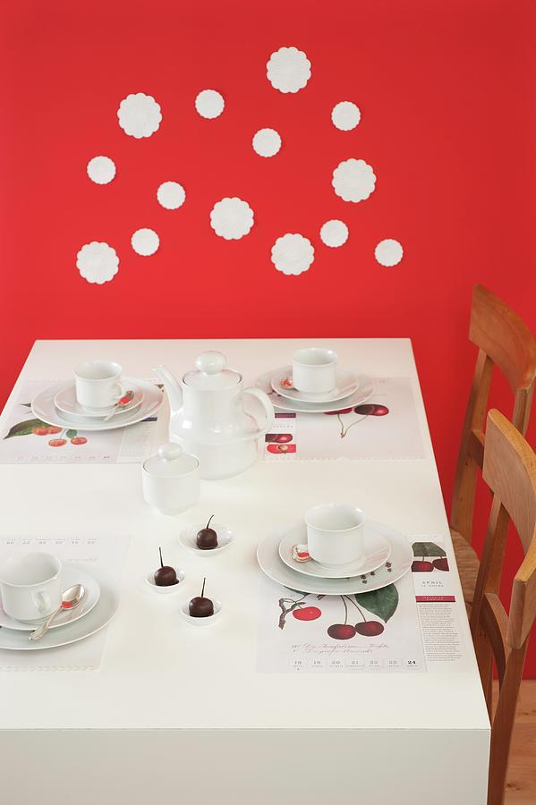 Table Set For Afternoon Coffee With Cherries Against Red Wall Decorated With White Doilies Photograph by Studio27neun