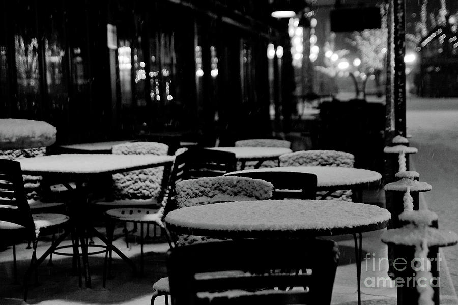 Tables and chairs of a cafe covered with snow during the night in winter. Photograph by Joaquin Corbalan