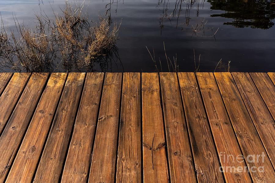 Tables of a wet wooden bridge over a lake. Photograph by Joaquin Corbalan