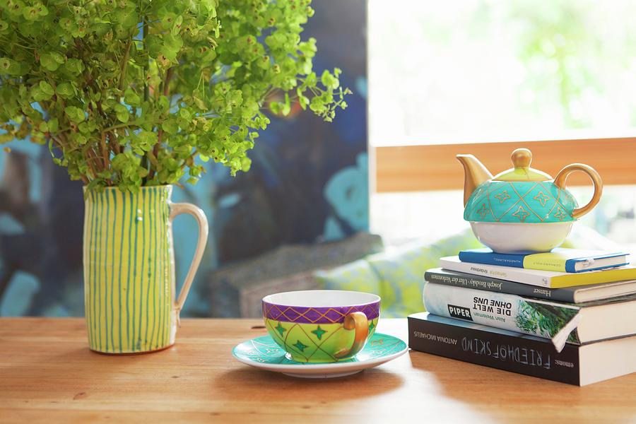 Teacup Next To Teapot On Stack Of Books And Ceramic Jug Of Ladys Mantle Photograph by Anneliese Kompatscher