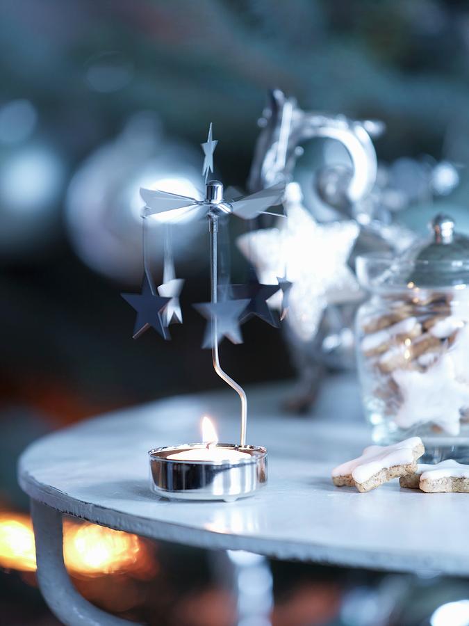 Tealight Carousel With Lit Candle Next To Storage Jar Of Festive Biscuits On Side Table Photograph by Matteo Manduzio
