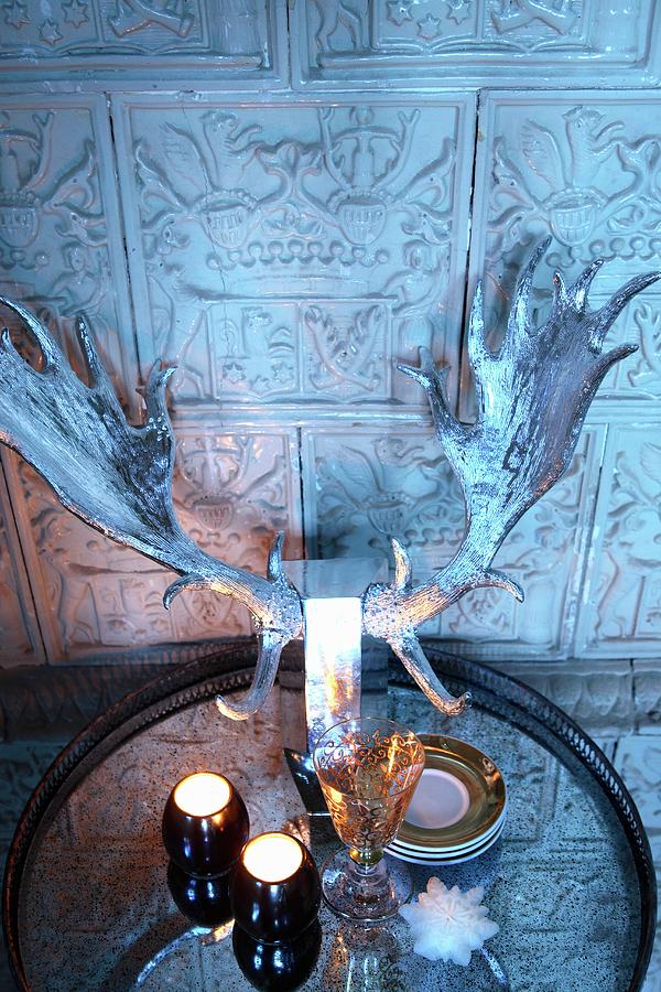 Tealights And Silvered Stags Antlers On Tray In Front Of Tiled Wall With Antique Embossed Motifs Photograph by Michal Mrowiec
