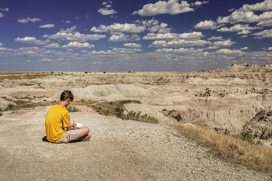 National Parks Photograph - Teen Boy Writes In Notebook Overlooking Badlands National Park, Usa by Cavan Images