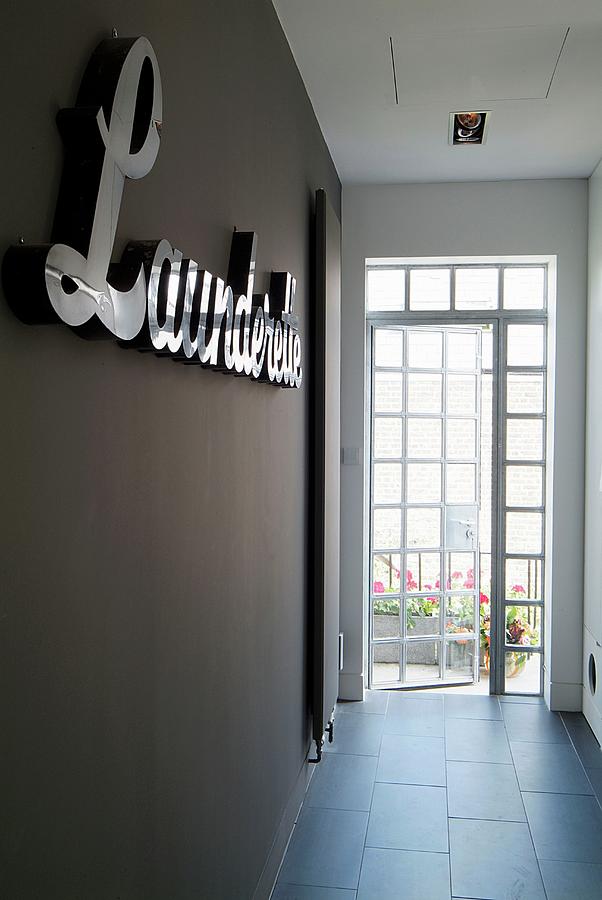 Terrace Door At End Of Modern Corridor With Grey Tiled Floor And Lettering On Dark Painted Wall Photograph by Wayne Vincent