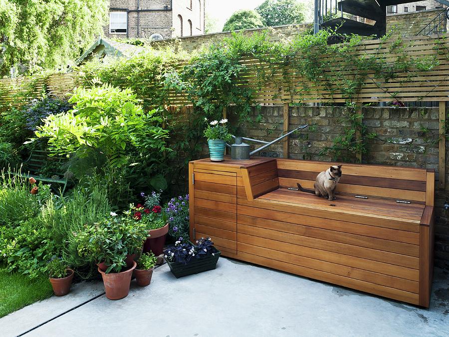 Terrace With Concrete Floor And Wooden Bench Structure With Storage For Garden Tools And Utensils Against Old Brick Wall Photograph by Simon Maxwell Photography