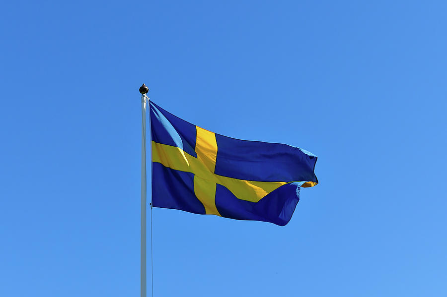 Summer Photograph - The Flag Of Sweden Flutters In The Wind Against A Beautiful Blue Sky, Bjurklubb, Vsterbottens Ln, Sweden by Torsten Rathjen