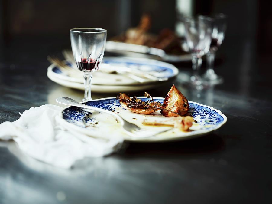 The Remains Of Roast Chicken With Lemons, Onions And Thyme, On Plates Photograph by Frank Weinert