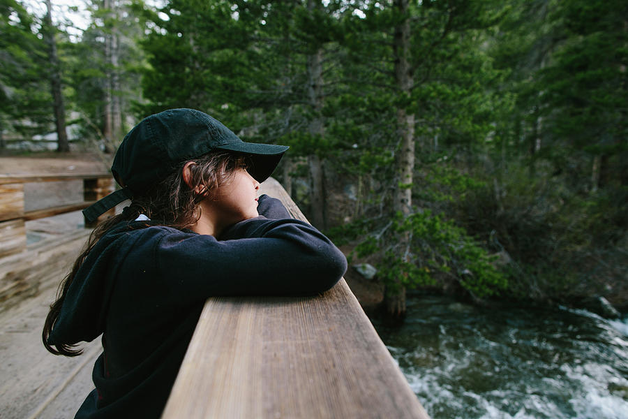 Nature Photograph - Thoughtful Girl In Cap Looking Away While Leaning On Bannister At Inyo National Forest by Cavan Images
