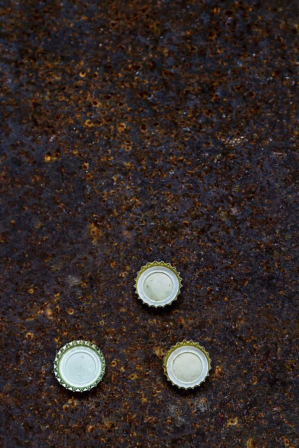 Three Beer Bottle Caps On A Piece Of Rusty Metal Photograph by Adel Bekefi
