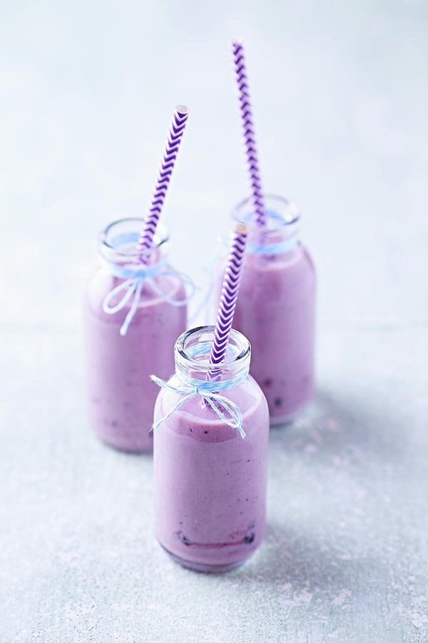 Three Blueberry Yoghurt Smoothies In Glass Bottles Photograph by B.&.e.dudzinski