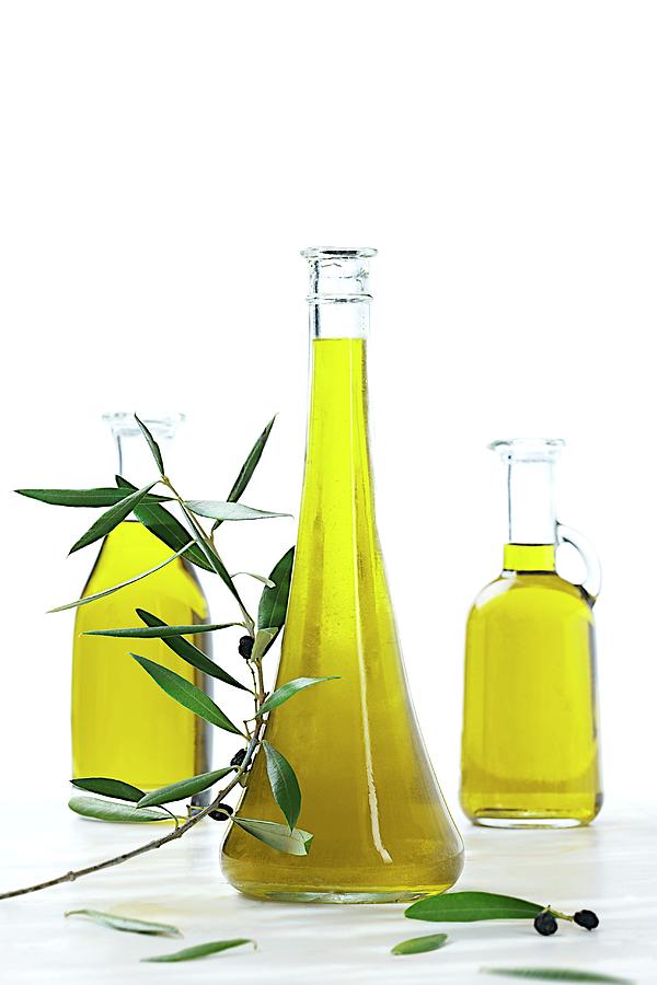 Three Bottles Of Olive Oil With An Olive Sprig Photograph by Jean-paul Chassenet