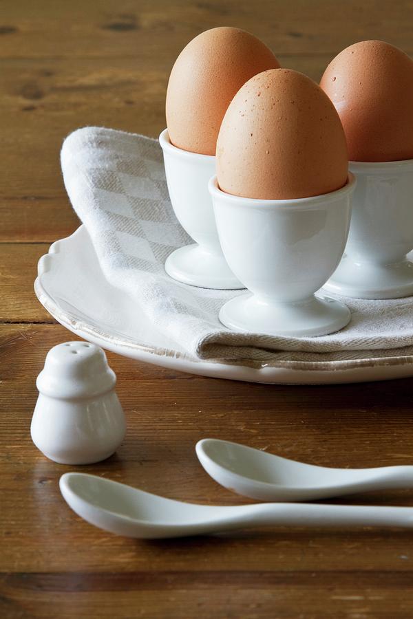 Three Brown Eggs In White Porcelain Egg Cups Photograph by Catja Vedder