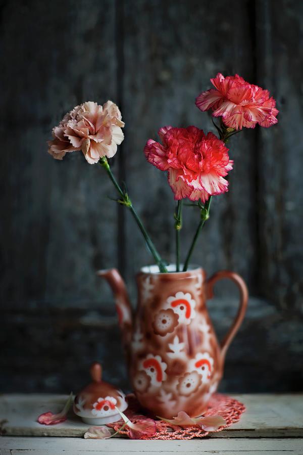 Three Carnations In Retro-style, Painted China Coffee Pot On Doily Against Dark Background Photograph by Sabine Lscher