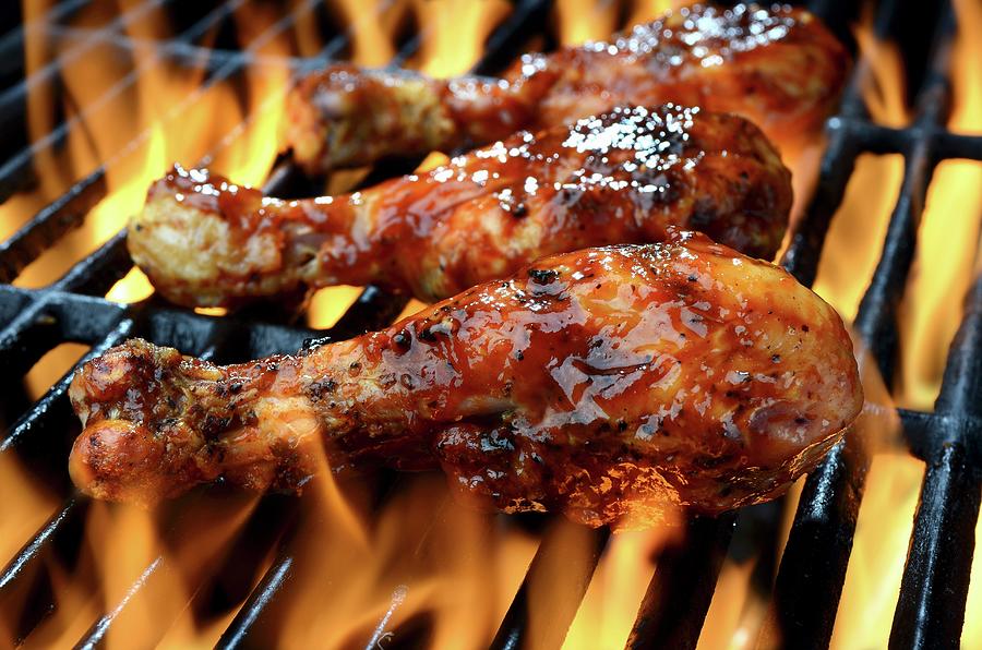 Three Chicken Legs In Bbq Sauce Cooking On A Flaming Grill Photograph by Brian Enright
