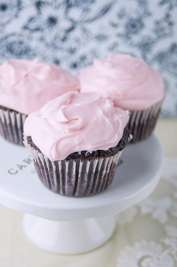 Three Chocolate Cupcakes With Pink Buttercream Frosting On A Cakestand Photograph by Jennifer Blume