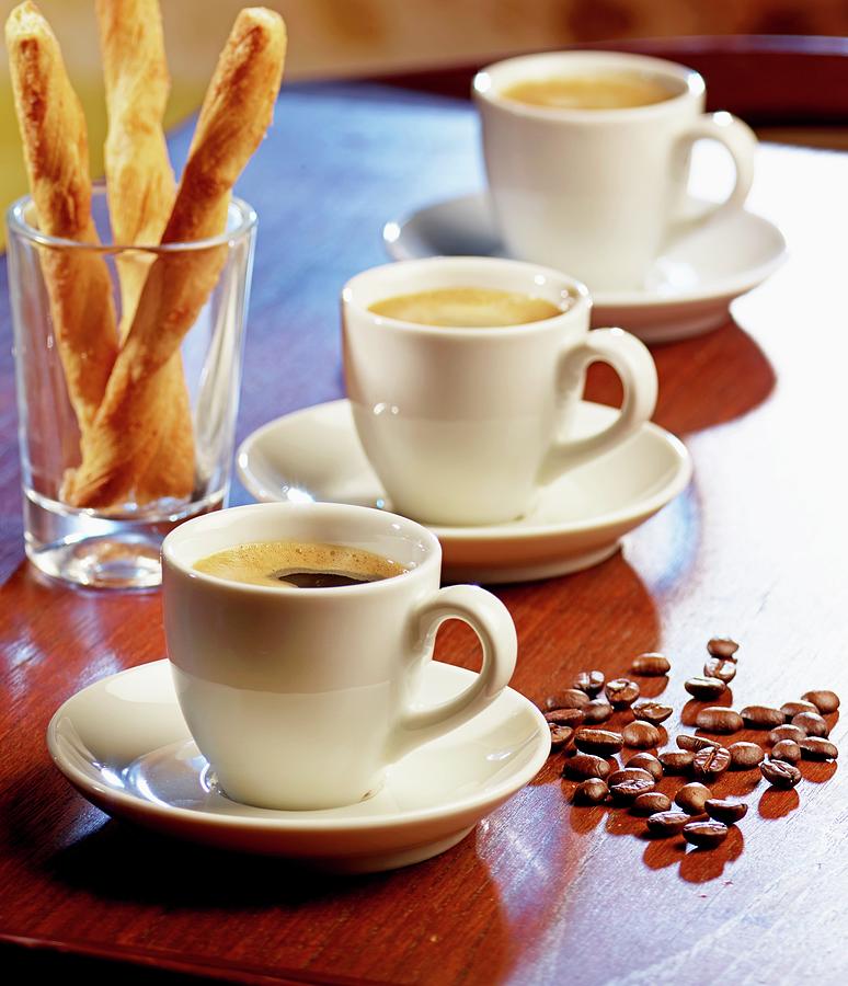 Three Espressos, Salted Breadsticks And Coffee Beans On A Table ...