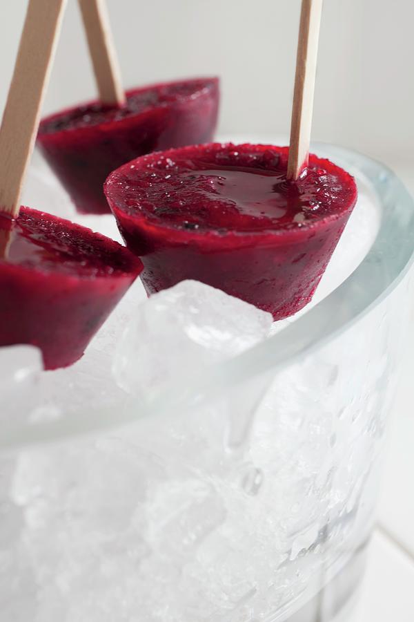 Three Grapefruit And Blackberry Ice Lollies In A Bowl Of Ice Photograph by Katharine Pollak